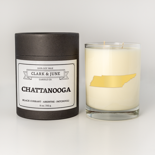 Double wicked soy candle in a 13.5 oz tumbler with the state of  Tennessee printed in 22k gold foil on the face. Black cylinder packaging with Chattanooga  on the label. SEO Text – Drinking glass, soy wax candle, Christmas Candle, hand poured, small batch, scented candle, Woman Owned, local candle, Housewarming present, gives back, charity, community candle, becomes a cocktail glass, closing gift.