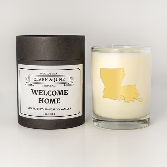 Double wicked soy candle in a 13.5 oz tumbler with the state of  Louisianaprinted in 22k gold foil on the face. Black cylinder packaging with Welcome Home  Louisianaon the label. SEO Text – Drinking glass, soy wax candle, Christmas Candle, hand poured, small batch, scented candle, Woman Owned, local candle, Housewarming present, gives back, charity, community candle, becomes a cocktail glass, closing gift.