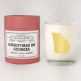 Load image into Gallery viewer, Double wicked soy candle in a 13.5 oz tumbler with the state of  Georgia printed in 22k gold foil on the face. Red cylinder packaging with Christmas in Georgia on the label. SEO Text – Drinking glass, soy wax candle, Christmas Candle, hand poured, small batch, scented candle, Woman Owned, local candle, Housewarming present, gives back, charity, community candle, becomes a cocktail glass, closing gift.
