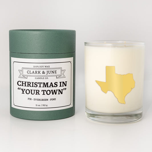 Double wicked soy candle in a 13.5 oz tumbler with the state of   Texas printed in 22k gold foil on the face. Green cylinder packaging with Christmas in "Your Town" on the label. SEO Text – Drinking glass, soy wax candle, Christmas Candle, hand poured, small batch, scented candle, Woman Owned, local candle, Housewarming present, gives back, charity, community candle, becomes a cocktail glass, closing gift.