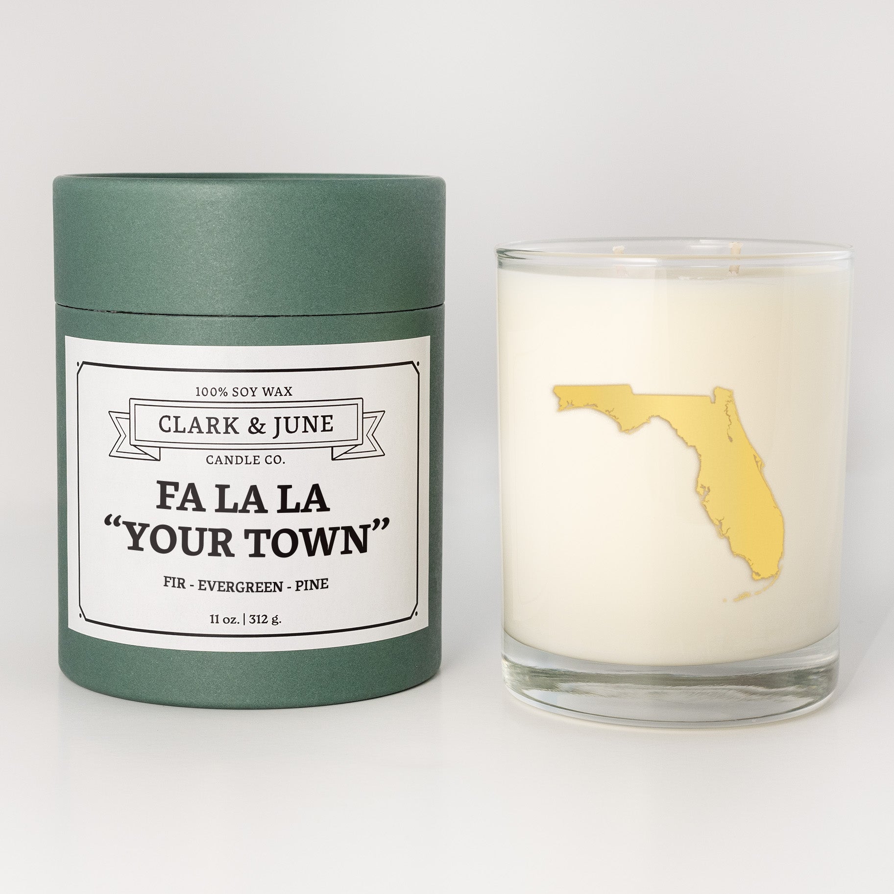 Double wicked soy candle in a 13.5 oz tumbler with the state of   Florida printed in 22k gold foil on the face. Green cylinder packaging with Fa La La "Your Town" on the label. SEO Text – Drinking glass, soy wax candle, Christmas Candle, hand poured, small batch, scented candle, Woman Owned, local candle, Housewarming present, gives back, charity, community candle, becomes a cocktail glass, closing gift.