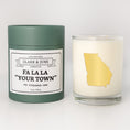 Load image into Gallery viewer, Double wicked soy candle in a 13.5 oz tumbler with the state of   Georgia printed in 22k gold foil on the face. Green cylinder packaging with Fa La La "Your Town" on the label. SEO Text – Drinking glass, soy wax candle, Christmas Candle, hand poured, small batch, scented candle, Woman Owned, local candle, Housewarming present, gives back, charity, community candle, becomes a cocktail glass, closing gift.