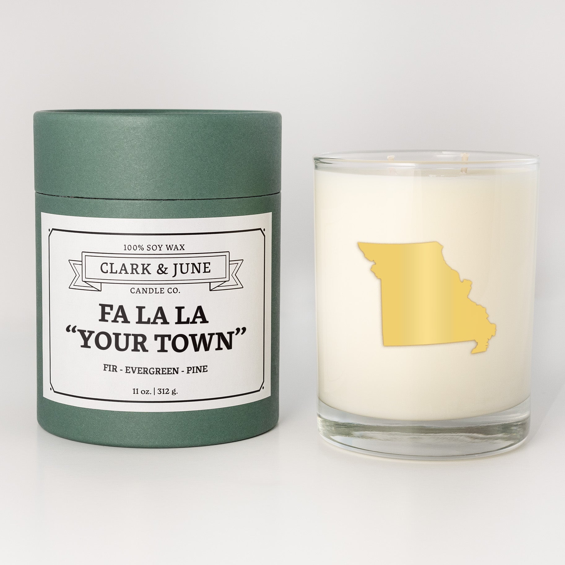 Double wicked soy candle in a 13.5 oz tumbler with the state of   Missouri printed in 22k gold foil on the face. Green cylinder packaging with Fa La La "Your Town" on the label. SEO Text – Drinking glass, soy wax candle, Christmas Candle, hand poured, small batch, scented candle, Woman Owned, local candle, Housewarming present, gives back, charity, community candle, becomes a cocktail glass, closing gift.