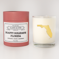 Load image into Gallery viewer, Double wicked soy candle in a 13.5 oz tumbler with the state of  Florida printed in 22k gold foil on the face. Red cylinder packaging with Happy Holidays Florida on the label. SEO Text – Drinking glass, soy wax candle, Christmas Candle, hand poured, small batch, scented candle, Woman Owned, local candle, Housewarming present, gives back, charity, community candle, becomes a cocktail glass, closing gift.