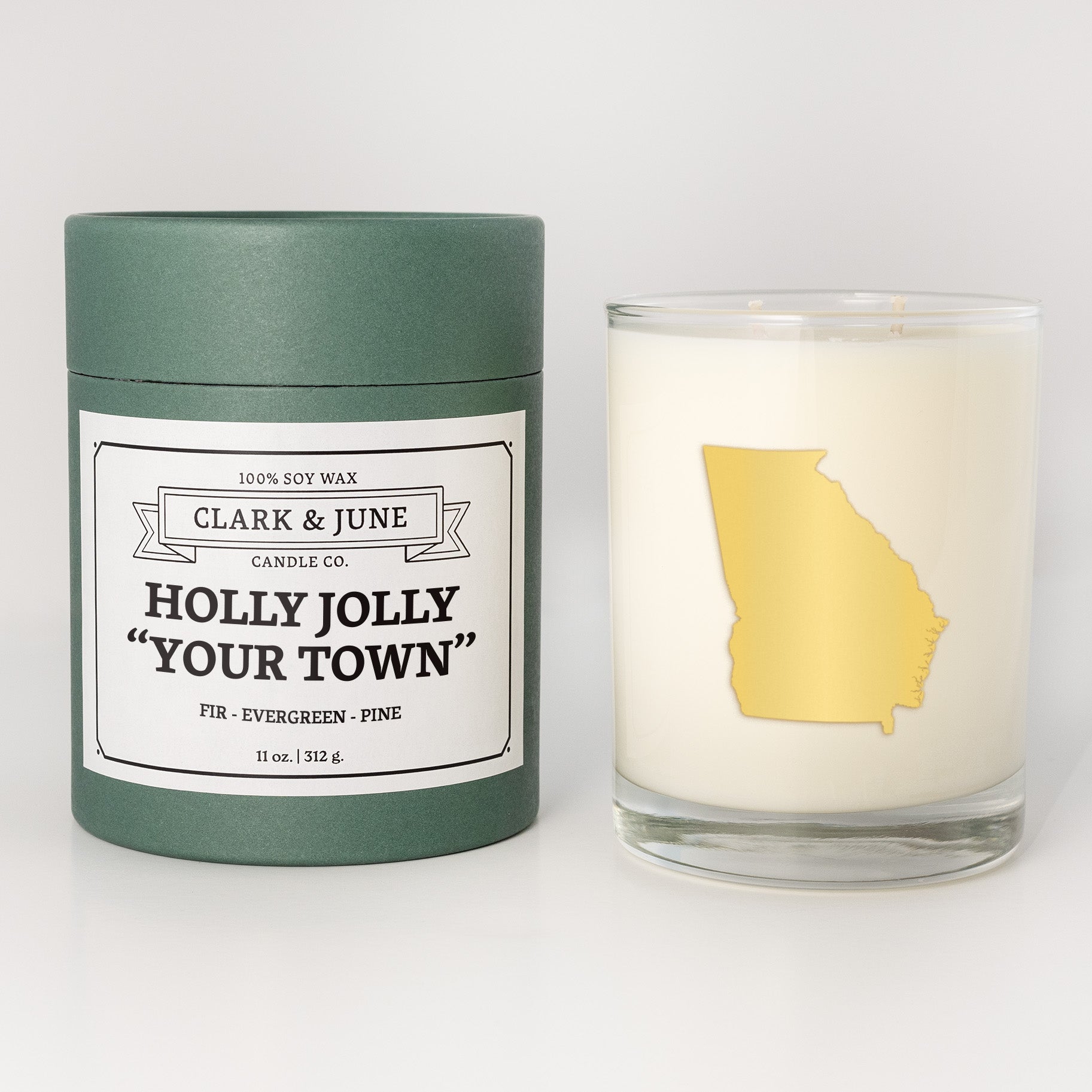 Double wicked soy candle in a 13.5 oz tumbler with the state of   Georgia printed in 22k gold foil on the face. Green cylinder packaging with Holly Jolly "Your Town" on the label. SEO Text – Drinking glass, soy wax candle, Christmas Candle, hand poured, small batch, scented candle, Woman Owned, local candle, Housewarming present, gives back, charity, community candle, becomes a cocktail glass, closing gift.