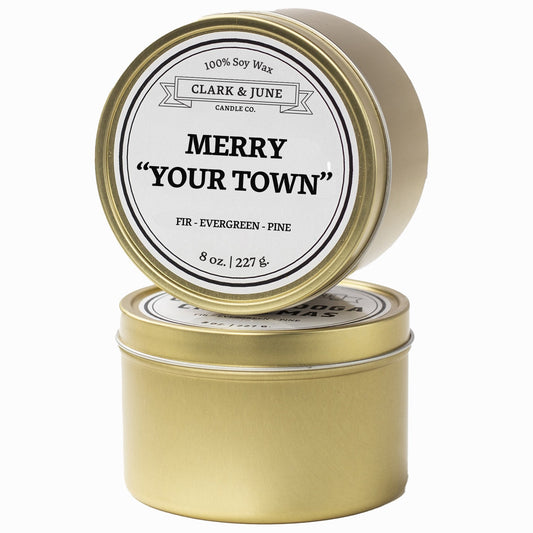 Single wicked Fir - Evergreen - Pine scented 8oz candle in gold finish with Merry "Your Town" on the label. SEO Text –soy wax candle, Christmas candle, Holiday candle hand poured, small batch, scented candle, Woman Owned, local candle, Housewarming present, gives back, charity, community candle, Soy wax candle Christmas gift.