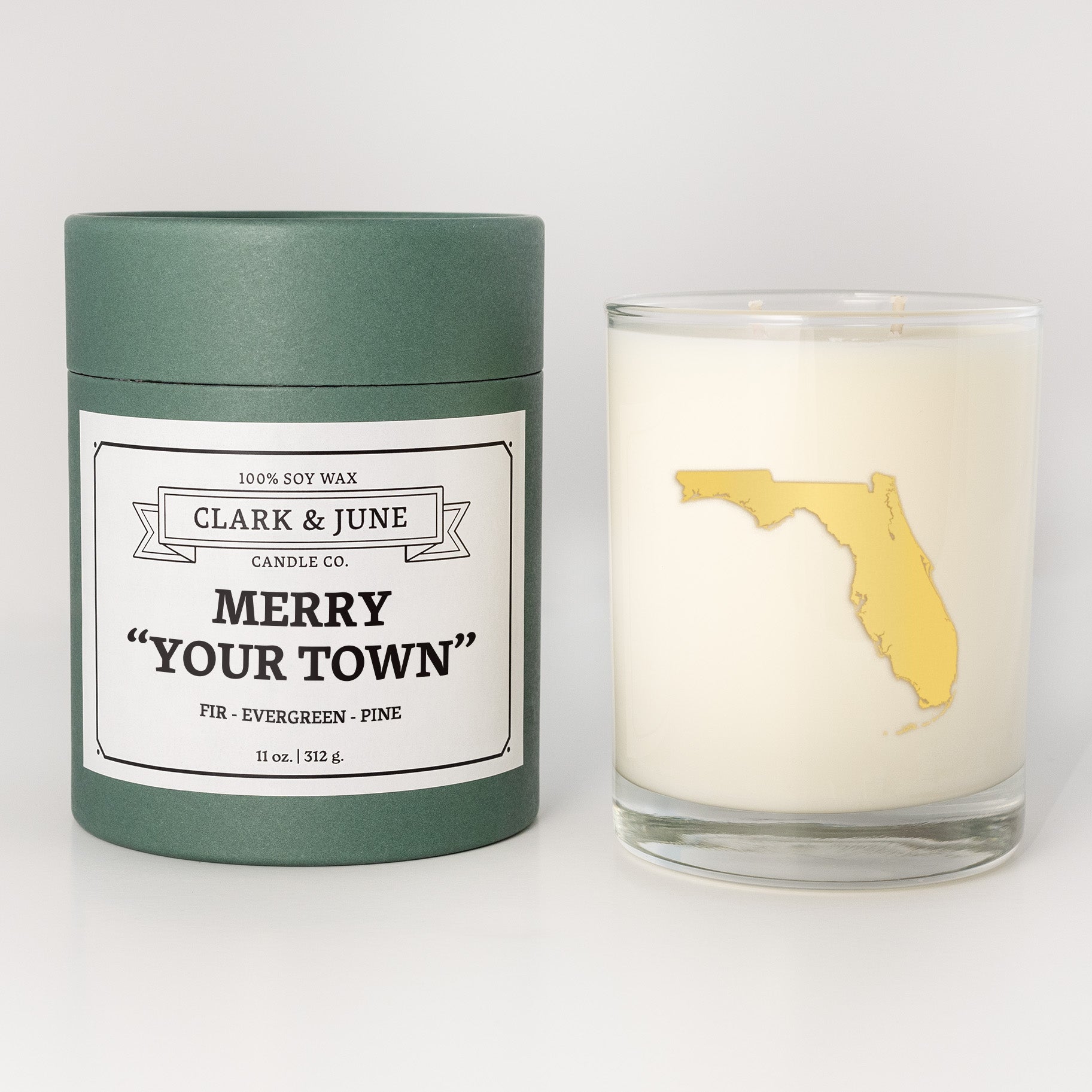 Double wicked soy candle in a 13.5 oz tumbler with the state of   Florida printed in 22k gold foil on the face. Green cylinder packaging with Merry "Your Town" on the label. SEO Text – Drinking glass, soy wax candle, Christmas Candle, hand poured, small batch, scented candle, Woman Owned, local candle, Housewarming present, gives back, charity, community candle, becomes a cocktail glass, closing gift.