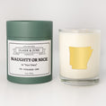 Load image into Gallery viewer, Double wicked soy candle in a 13.5 oz tumbler with the state of   Arkansas printed in 22k gold foil on the face. Green cylinder packaging with Naughty or Nice in "Your Town" on the label. SEO Text – Drinking glass, soy wax candle, Christmas Candle, hand poured, small batch, scented candle, Woman Owned, local candle, Housewarming present, gives back, charity, community candle, becomes a cocktail glass, closing gift.