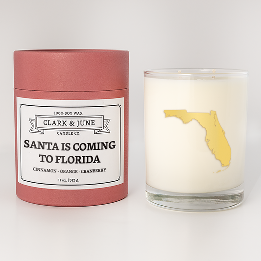 Double wicked soy candle in a 13.5 oz tumbler with the state of  Florida printed in 22k gold foil on the face. Red cylinder packaging with Santa is Coming to Florida on the label. SEO Text – Drinking glass, soy wax candle, Christmas Candle, hand poured, small batch, scented candle, Woman Owned, local candle, Housewarming present, gives back, charity, community candle, becomes a cocktail glass, closing gift.