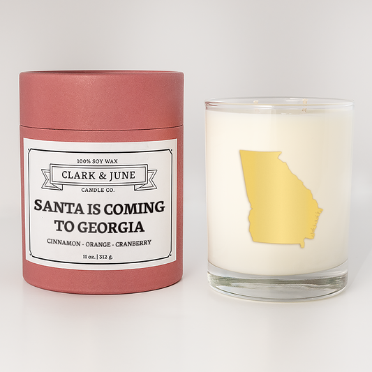 Double wicked soy candle in a 13.5 oz tumbler with the state of  Georgia printed in 22k gold foil on the face. Red cylinder packaging with Santa is Coming to Georgia on the label. SEO Text – Drinking glass, soy wax candle, Christmas Candle, hand poured, small batch, scented candle, Woman Owned, local candle, Housewarming present, gives back, charity, community candle, becomes a cocktail glass, closing gift.