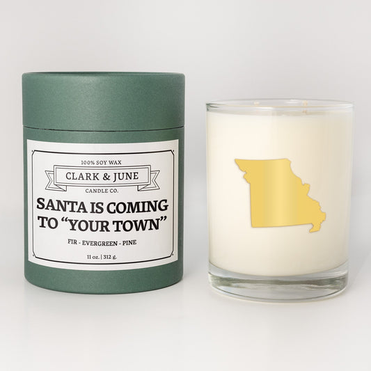 Double wicked soy candle in a 13.5 oz tumbler with the state of Missouriprinted in 22k gold foil on the face. Green cylinder packaging with Santa is Coming to "Your Town"on the label. SEO Text – Drinking glass, soy wax candle, Christmas Candle, hand poured, small batch, scented candle, Woman Owned, local candle, Housewarming present, gives back, charity, community candle, becomes a cocktail glass, closing gift.