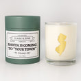 Load image into Gallery viewer, Double wicked soy candle in a 13.5 oz tumbler with the state of   New Jersey printed in 22k gold foil on the face. Green cylinder packaging with Santa is Coming to "Your Town" on the label. SEO Text – Drinking glass, soy wax candle, Christmas Candle, hand poured, small batch, scented candle, Woman Owned, local candle, Housewarming present, gives back, charity, community candle, becomes a cocktail glass, closing gift.