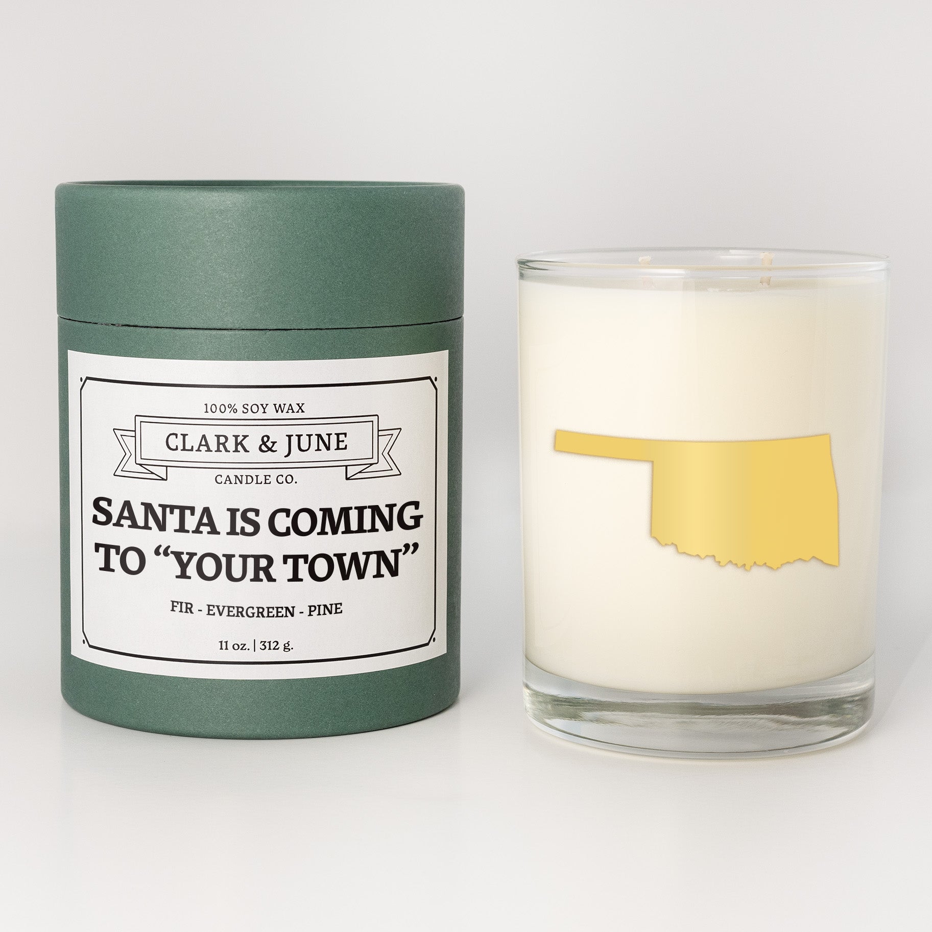 Double wicked soy candle in a 13.5 oz tumbler with the state of   Oklahoma printed in 22k gold foil on the face. Green cylinder packaging with Santa is Coming to "Your Town" on the label. SEO Text – Drinking glass, soy wax candle, Christmas Candle, hand poured, small batch, scented candle, Woman Owned, local candle, Housewarming present, gives back, charity, community candle, becomes a cocktail glass, closing gift.