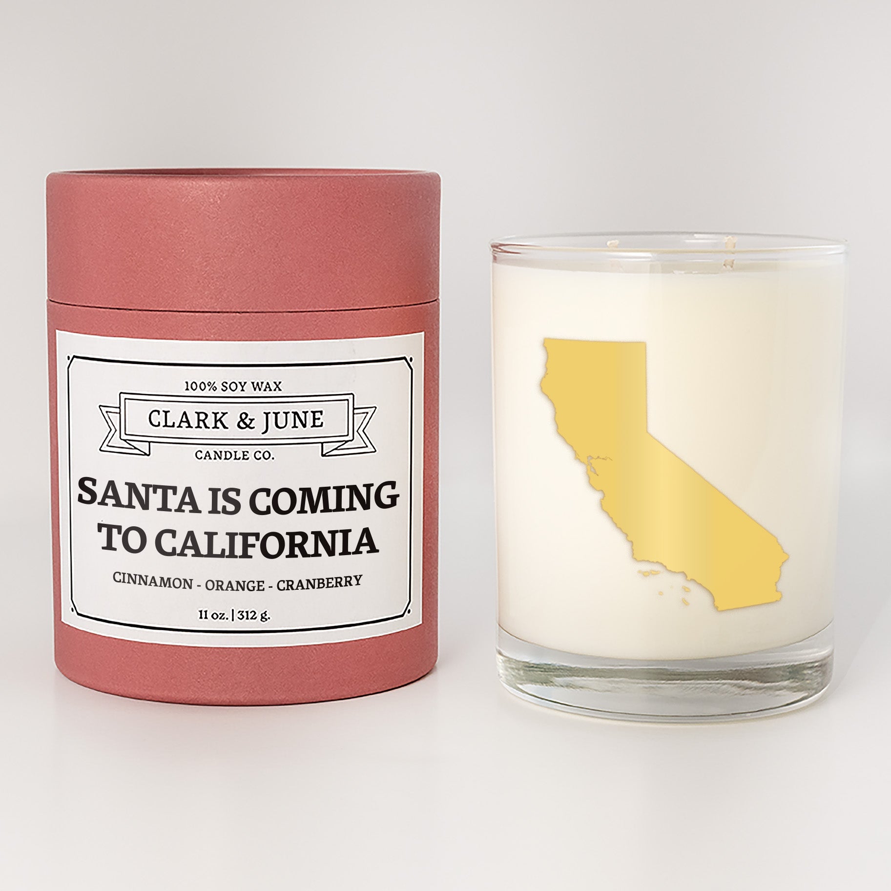 Double wicked soy candle in a 13.5 oz tumbler with the state of  California printed in 22k gold foil on the face. Red cylinder packaging with Santa is Coming to California on the label. SEO Text – Drinking glass, soy wax candle, Christmas Candle, hand poured, small batch, scented candle, Woman Owned, local candle, Housewarming present, gives back, charity, community candle, becomes a cocktail glass, closing gift.