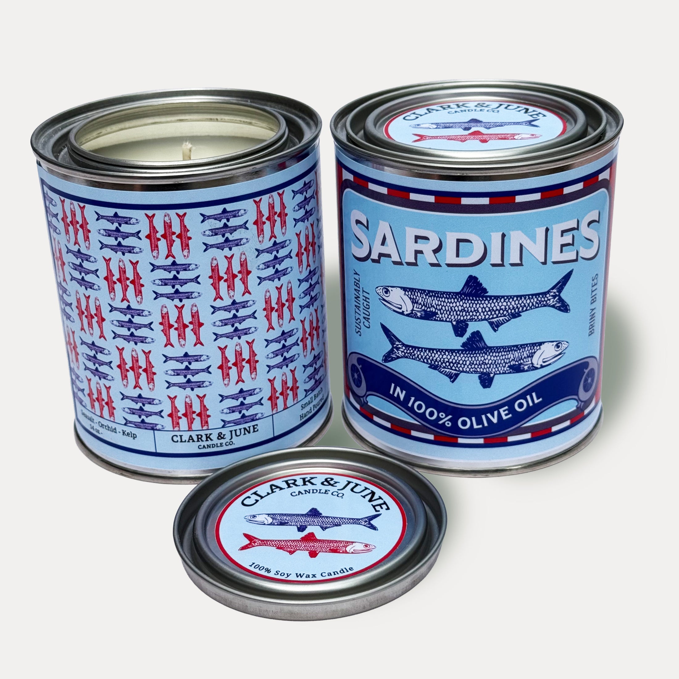14oz Sardine design soy wax candle in a pint sized paint can made by Clark & June Candle Co. The candle is wrapped with a blue and red label showing a repeating pattern of blue and red sardines on the back and a recreation of a can of sardines in olive oil on the front. The scent is Seasalt – Orchid - Kelp and was hand poured in small batches. 
Sardine Candle, Scented Candle, Paint Can Candle. Single Cotton Wick, Fish Core
