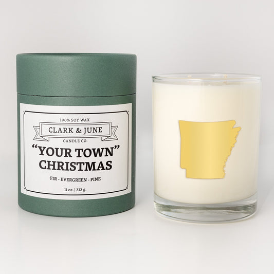 Double wicked soy candle in a 13.5 oz tumbler with the state of Arkansasprinted in 22k gold foil on the face. Green cylinder packaging with "Your Town" Christmas on the label. SEO Text – Drinking glass, soy wax candle, Christmas Candle, hand poured, small batch, scented candle, Woman Owned, local candle, Housewarming present, gives back, charity, community candle, becomes a cocktail glass, closing gift.