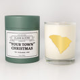 Load image into Gallery viewer, Double wicked soy candle in a 13.5 oz tumbler with the state of   South Carolinaprinted in 22k gold foil on the face. Green cylinder packaging with "Your Town" Christmas on the label. SEO Text – Drinking glass, soy wax candle, Christmas Candle, hand poured, small batch, scented candle, Woman Owned, local candle, Housewarming present, gives back, charity, community candle, becomes a cocktail glass, closing gift.