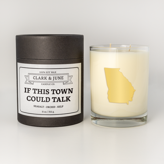 Double wicked soy candle in a 13.5 oz tumbler with the state of Georgia printed in 22k gold foil on the face. Black cylinder packaging with “If This Town Could Talk” on the label. SEO Text – Drinking glass, soy wax candle, Georgia candle, hand poured, small batch, scented candle, Woman Owned, local candle, Housewarming present, gives back, charity, community candle, becomes a cocktail glass, closing gift. 