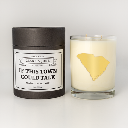 Double wicked soy candle in a 13.5 oz tumbler with the state of South Carolina printed in 22k gold foil on the face. Black cylinder packaging with “If This Town Could Talk” on the label. SEO Text – Drinking glass, soy wax candle, South Carolina candle, hand poured, small batch, scented candle, Woman Owned, local candle, Housewarming present, gives back, charity, community candle, becomes a cocktail glass, closing gift.