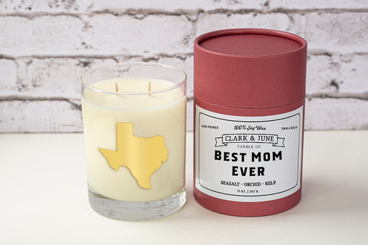 Double wicked soy candle in a 13.5 oz tumbler with the state of Texas printed in 22k gold foil on the face. Black cylinder packaging with “Best Mom Ever” on the label. SEO Text – Drinking glass, soy wax candle, Texas candle, hand poured, small batch, scented candle, Woman Owned, local candle, Housewarming present, gives back, charity, community candle, becomes a cocktail glass, closing gift. Mother's Day Candle, Mothers Day 