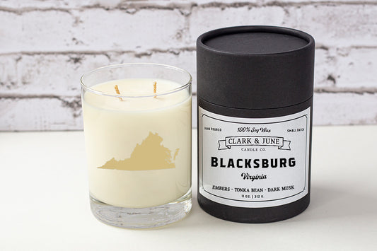 Double wicked soy candle in a 13.5 oz tumbler with the state of Virginia printed in 22k gold foil on the face. Black cylinder packaging with “Blacksburg, Virginia” on the label. SEO Text – Drinking glass, soy wax candle, Virginia candle, hand poured, small batch, scented candle, Woman Owned, local candle, Housewarming present, gives back, charity, community candle, becomes a cocktail glass, closing gift.