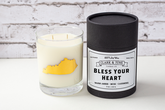 Double wicked soy candle in a 13.5 oz tumbler with the state of Kentucky printed in 22k gold foil on the face. Black cylinder packaging with “Bless Your Heart” on the label. SEO Text – Drinking glass, soy wax candle, Kentucky candle, hand poured, small batch, scented candle, Woman Owned, local candle, Housewarming present, gives back, charity, community candle, becomes a cocktail glass, closing gift. 