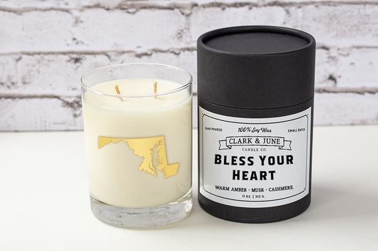 Double wicked soy candle in a 13.5 oz tumbler with the state of Maryland printed in 22k gold foil on the face. Black cylinder packaging with “Bless Your Heart” on the label. SEO Text – Drinking glass, soy wax candle, Maryland candle, hand poured, small batch, scented candle, Woman Owned, local candle, Housewarming present, gives back, charity, community candle, becomes a cocktail glass, closing gift.