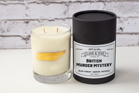 Double wicked soy candle in a 13.5 oz tumbler with the state of Tennessee printed in 22k gold foil on the face. Black cylinder packaging with “British Murder Mystery” on the label. 