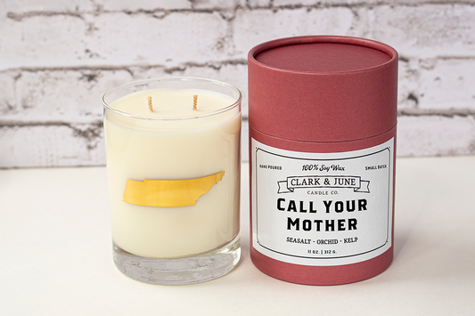 Double wicked soy candle in a 13.5 oz tumbler with the state of Tennessee printed in 22k gold foil on the face. Red cylinder packaging with “Call Your Mother” on the label. 