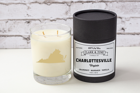 Double wicked soy candle in a 13.5 oz tumbler with the state of Virginia printed in 22k gold foil on the face. Black cylinder packaging with “Charlottesville, Virginia” on the label. SEO Text – Drinking glass, soy wax candle, Virginia candle, hand poured, small batch, scented candle, Woman Owned, local candle, Housewarming present, gives back, charity, community candle, becomes a cocktail glass, closing gift.