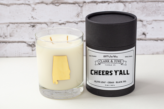 Double wicked soy candle in a 13.5 oz tumbler with the state of Alabama printed in 22k gold foil on the face. Black cylinder packaging with “Cheers Y’All” on the label. SEO Text – Drinking glass, soy wax candle, Alabama candle, hand poured, small batch, scented candle, Woman Owned, local candle, Housewarming present, gives back, charity, community candle, becomes a cocktail glass, closing gift. 