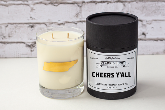 Double wicked soy candle in a 13.5 oz tumbler with the state of Tennessee printed in 22k gold foil on the face. Black cylinder packaging with “Cheers Y’All” on the label. SEO Text – Drinking glass, soy wax candle, Tennessee candle, hand poured, small batch, scented candle, Woman Owned, local candle, Housewarming present, gives back, charity, community candle, becomes a cocktail glass, closing gift.