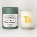 Load image into Gallery viewer, Double wicked soy candle in a 13.5 oz tumbler with the state of Missouriprinted in 22k gold foil on the face. Green cylinder packaging with Fa La La "Your Town"on the label. SEO Text – Drinking glass, soy wax candle, Christmas Candle, hand poured, small batch, scented candle, Woman Owned, local candle, Housewarming present, gives back, charity, community candle, becomes a cocktail glass, closing gift. 
