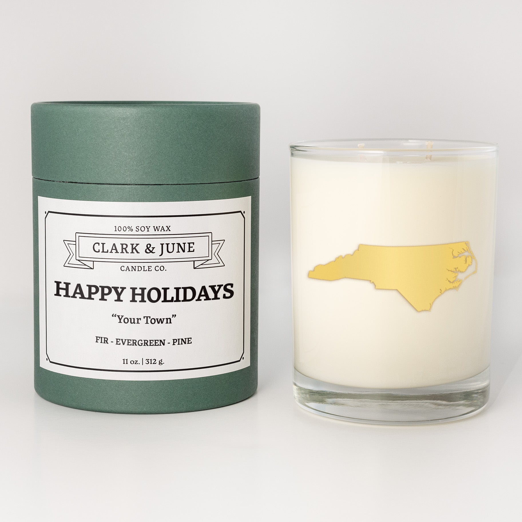 Double wicked soy candle in a 13.5 oz tumbler with the state of   North Carolina printed in 22k gold foil on the face. Green cylinder packaging with Happy Holidays in "Your Town" on the label. SEO Text â€“ Drinking glass, soy wax candle, Christmas Candle, hand poured, small batch, scented candle, Woman Owned, local candle, Housewarming present, gives back, charity, community candle, becomes a cocktail glass, closing gift. 
