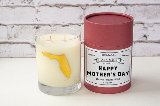 Double wicked soy candle in a 13.5 oz tumbler with the state of Florida printed in 22k gold foil on the face. Black cylinder packaging with “Happy Mother’s Day” on the label. SEO Text – Drinking glass, soy wax candle, Florida candle, hand poured, small batch, scented candle, Woman Owned, local candle, Housewarming present, gives back, charity, community candle, becomes a cocktail glass, closing gift. 