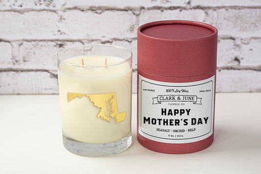 Double wicked soy candle in a 13.5 oz tumbler with the state of Maryland printed in 22k gold foil on the face. Black cylinder packaging with “Happy Mother’s Day” on the label. SEO Text – Drinking glass, soy wax candle, Maryland candle, hand poured, small batch, scented candle, Woman Owned, local candle, Housewarming present, gives back, charity, community candle, becomes a cocktail glass, closing gift.