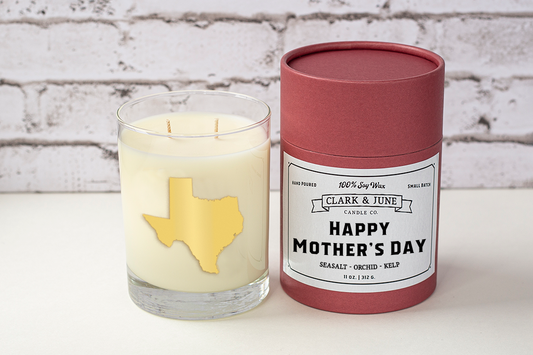 Double wicked soy candle in a 13.5 oz tumbler with the state of Texas printed in 22k gold foil on the face. Black cylinder packaging with “Happy Mother’s Day” on the label. SEO Text – Drinking glass, soy wax candle, Texas candle, hand poured, small batch, scented candle, Woman Owned, local candle, Housewarming present, gives back, charity, community candle, becomes a cocktail glass, closing gift.