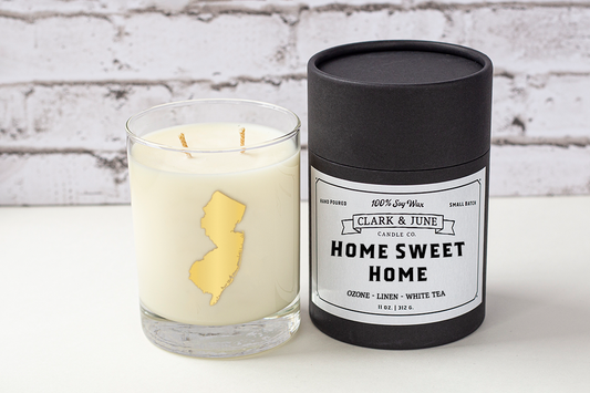 Double wicked soy candle in a 13.5 oz tumbler with the state of New Jersey printed in 22k gold foil on the face. Black cylinder packaging with “Home Sweet Home” on the label. SEO Text – Drinking glass, soy wax candle, New Jersey candle, hand poured, small batch, scented candle, Woman Owned, local candle, Housewarming present, gives back, charity, community candle, becomes a cocktail glass, closing gift.
