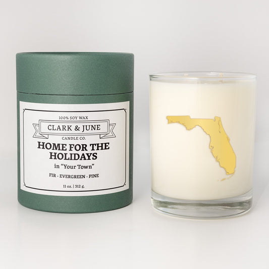 Double wicked soy candle in a 13.5 oz tumbler with the state of Floridaprinted in 22k gold foil on the face. Green cylinder packaging with Home for the Holidays in "Your Town"on the label. SEO Text – Drinking glass, soy wax candle, Christmas Candle, hand poured, small batch, scented candle, Woman Owned, local candle, Housewarming present, gives back, charity, community candle, becomes a cocktail glass, closing gift. 