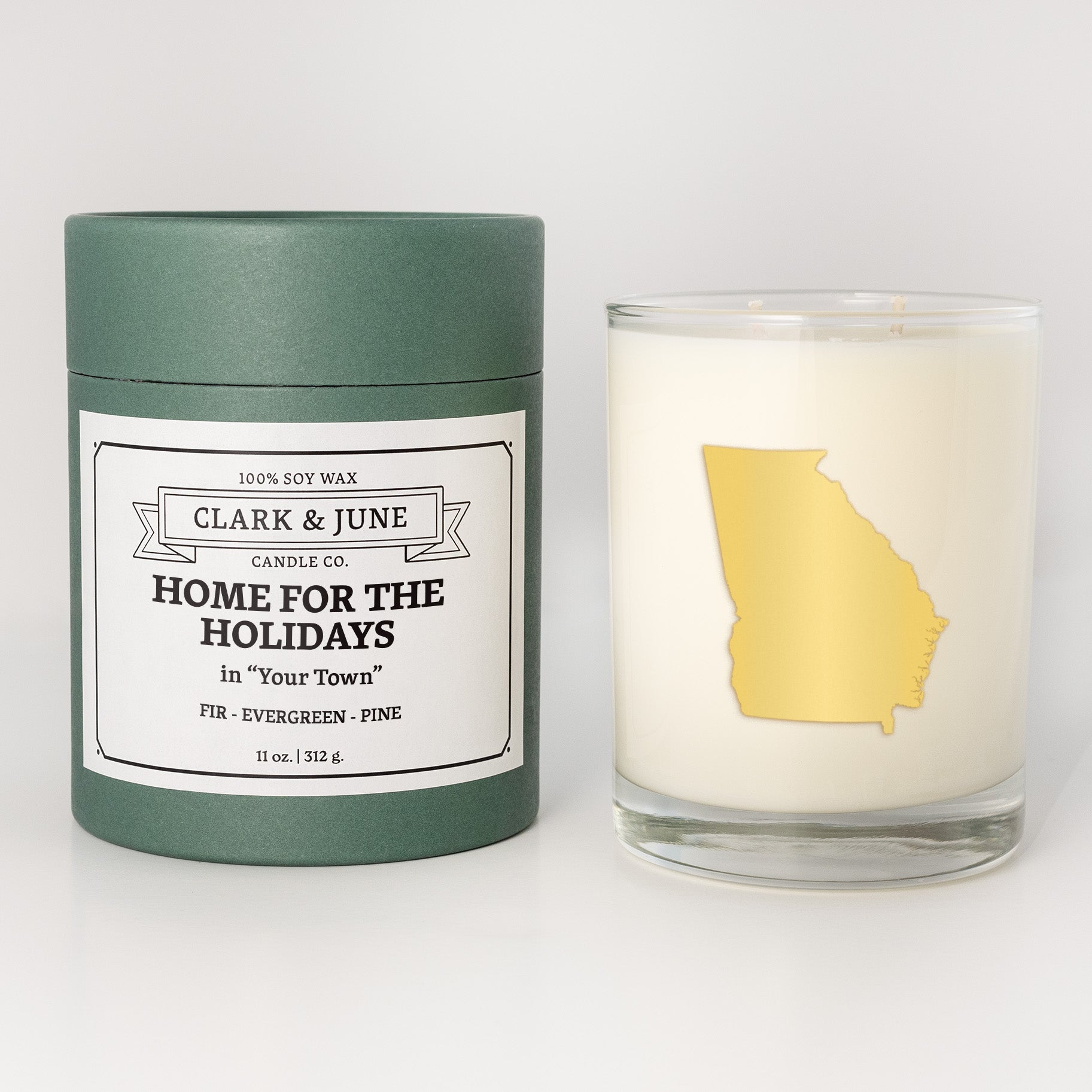Double wicked soy candle in a 13.5 oz tumbler with the state of  Georgia printed in 22k gold foil on the face. Red cylinder packaging with Home for the Holidays in "Your Town" on the label. SEO Text â€“ Drinking glass, soy wax candle, Christmas Candle, hand poured, small batch, scented candle, Woman Owned, local candle, Housewarming present, gives back, charity, community candle, becomes a cocktail glass, closing gift. 
