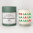 Load image into Gallery viewer, Double wicked soy candle in a 13.5 oz tumbler with Fa La La printed on the face. Green cylinder packaging with It's a Wonderful Life in "Your Town" on the label. SEO Text – Drinking glass, soy wax candle, Christmas Candle, hand poured, small batch, scented candle, Woman Owned, local candle, Housewarming present, gives back, charity, community candle, becomes a cocktail glass, closing gift. 
