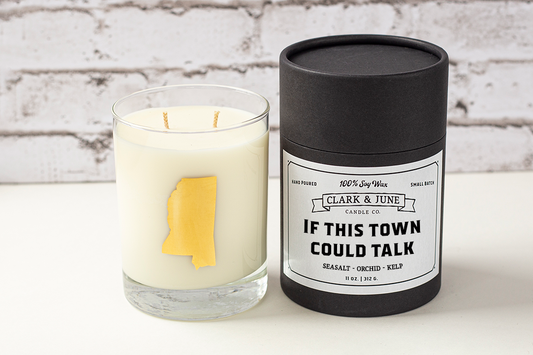 Double wicked soy candle in a 13.5 oz tumbler with the state of Mississippi printed in 22k gold foil on the face. Black cylinder packaging with “If This Town Could Talk” on the label. SEO Text – Drinking glass, soy wax candle, Mississippi candle, hand poured, small batch, scented candle, Woman Owned, local candle, Housewarming present, gives back, charity, community candle, becomes a cocktail glass, closing gift. 