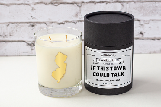 Double wicked soy candle in a 13.5 oz tumbler with the state of New Jersey printed in 22k gold foil on the face. Black cylinder packaging with “If This Town Could Talk” on the label. SEO Text – Drinking glass, soy wax candle, New Jersey candle, hand poured, small batch, scented candle, Woman Owned, local candle, Housewarming present, gives back, charity, community candle, becomes a cocktail glass, closing gift.