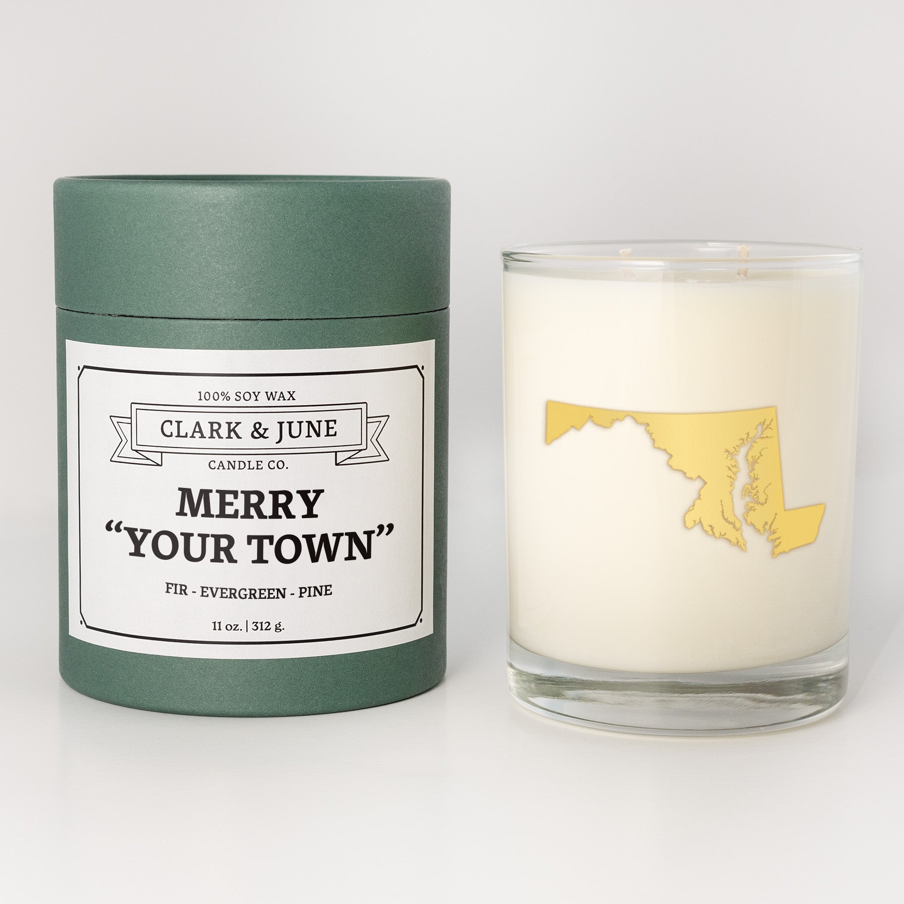 Double wicked soy candle in a 13.5 oz tumbler with the state of   Maryland printed in 22k gold foil on the face. Green cylinder packaging with Merry "Your Town" on the label. SEO Text â€“ Drinking glass, soy wax candle, Christmas Candle, hand poured, small batch, scented candle, Woman Owned, local candle, Housewarming present, gives back, charity, community candle, becomes a cocktail glass, closing gift. 
