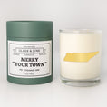 Load image into Gallery viewer, Double wicked soy candle in a 13.5 oz tumbler with the state of   Tennessee printed in 22k gold foil on the face. Green cylinder packaging with Merry "Your Town" on the label. SEO Text â€“ Drinking glass, soy wax candle, Christmas Candle, hand poured, small batch, scented candle, Woman Owned, local candle, Housewarming present, gives back, charity, community candle, becomes a cocktail glass, closing gift. 

