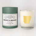 Load image into Gallery viewer, Double wicked soy candle in a 13.5 oz tumbler with the state of Arkansasprinted in 22k gold foil on the face. Green cylinder packaging with Merry & Bright in "Your Town"on the label. SEO Text – Drinking glass, soy wax candle, Christmas Candle, hand poured, small batch, scented candle, Woman Owned, local candle, Housewarming present, gives back, charity, community candle, becomes a cocktail glass, closing gift. 
