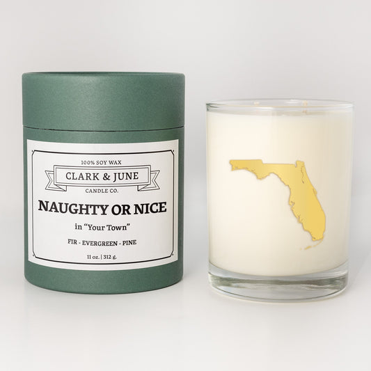 Double wicked soy candle in a 13.5 oz tumbler with the state of Floridaprinted in 22k gold foil on the face. Green cylinder packaging with Naughty or Nice in "Your Town" on the label. SEO Text – Drinking glass, soy wax candle, Christmas Candle, hand poured, small batch, scented candle, Woman Owned, local candle, Housewarming present, gives back, charity, community candle, becomes a cocktail glass, closing gift. 