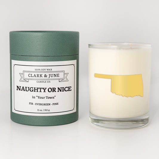 Double wicked soy candle in a 13.5 oz tumbler with the state of Oklahomaprinted in 22k gold foil on the face. Green cylinder packaging with Naughty or Nice in "Your Town" on the label. SEO Text – Drinking glass, soy wax candle, Christmas Candle, hand poured, small batch, scented candle, Woman Owned, local candle, Housewarming present, gives back, charity, community candle, becomes a cocktail glass, closing gift. 