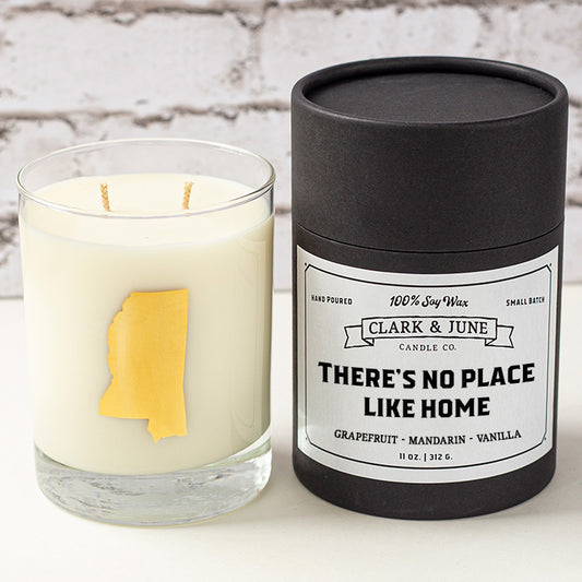 Double wicked soy candle in a 13.5 oz tumbler with the state of Mississippi printed in 22k gold foil on the face. Black cylinder packaging with "There's No Place Like Home"on the label. SEO Text – Drinking glass, soy wax candle, Mississippi candle, hand poured, small batch, scented candle, Woman Owned, local candle, Housewarming present, gives back, charity, community candle, becomes a cocktail glass, closing gift. 