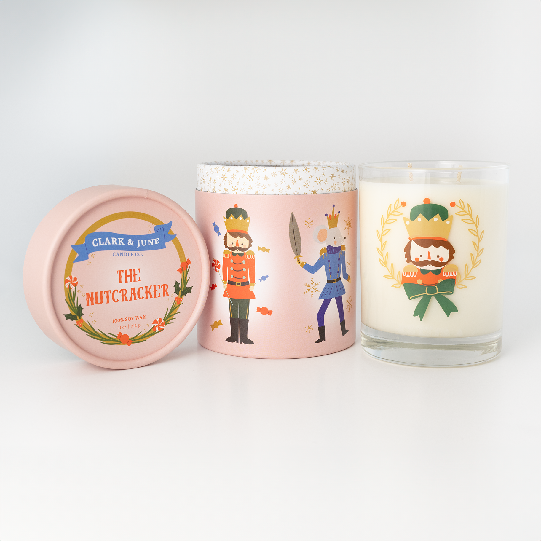 Double wicked soy candle in a 13.5 oz tumbler with a Nutcracker Face printed on the glass. Pink Nutcracker Suite themed packaging. SEO Text â€“ Drinking glass, soy wax candle, Christmas Candle, hand poured, small batch, scented candle, Woman Owned, local candle, Holiday Candle, gives back, charity, community candle, becomes a cocktail glass